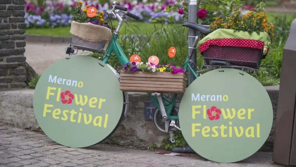 Fahrrad mit Blumenkörben und Schildern des Merano Flower Festival in Meran.