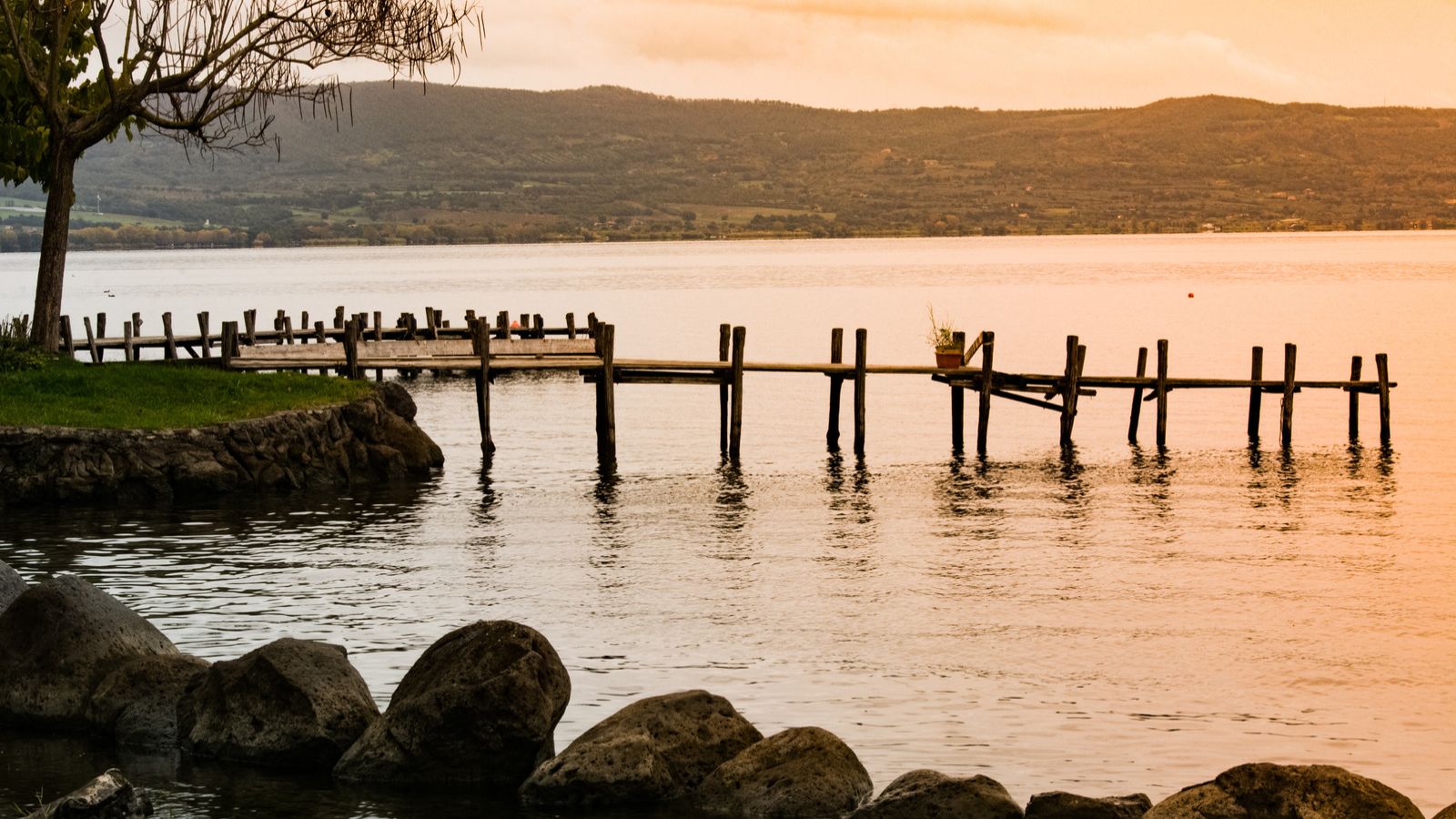 Ruhiges Ufer des Lago di Bolsena mit Stegen und bewaldeter Landschaft
